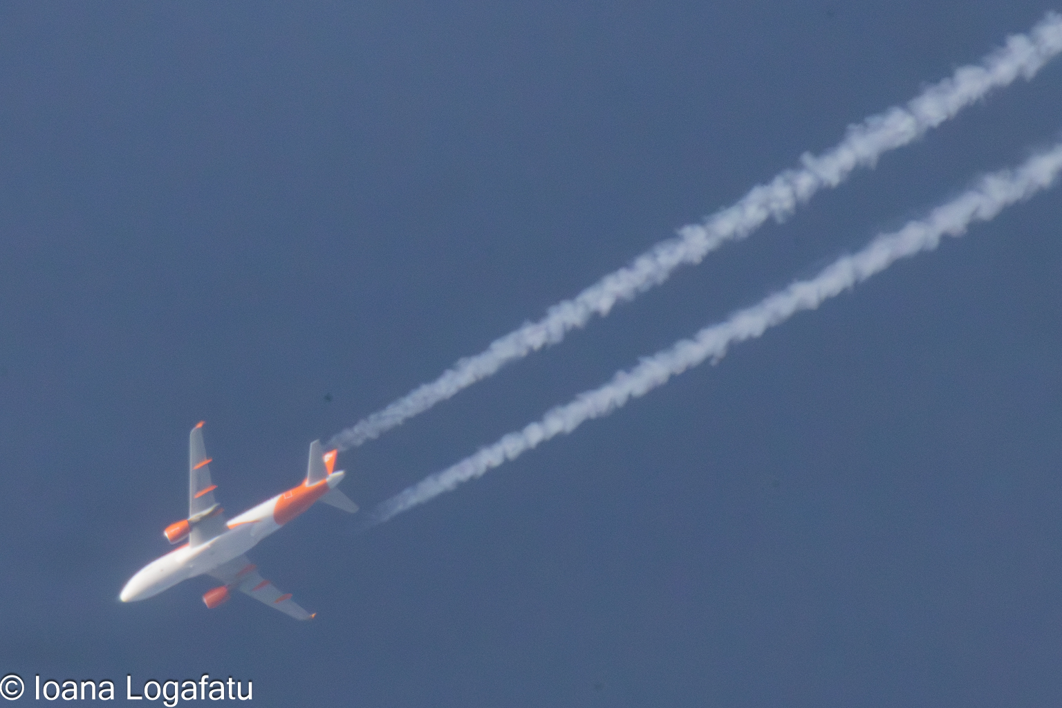 Airplane soaring high above in a clear blue sky